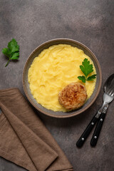 Mashed potatoes with fried cutlet in a bowl on a dark grunge background. Top view, flat lay, vertical