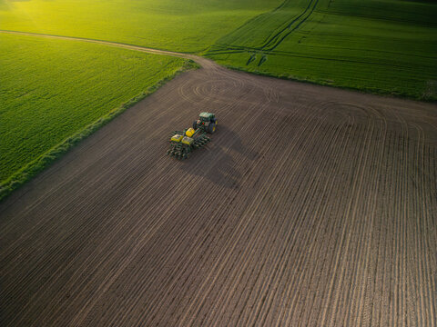 Ontario Canada May 13 2022: Aerial view of a large modern John Deere tractor plowing farmland field in spring season. Drone photo. Farming, agriculture concept.
