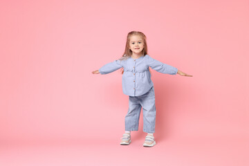 Cute little girl dancing on pink background