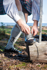 Man wearing scottish costume and kilt lace up his shoe for Scottish dance