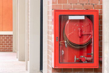 A red fire hydrant is mounted on a brick wall