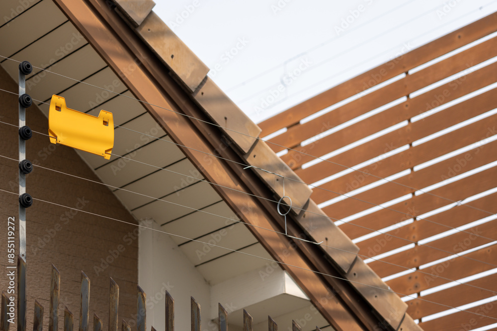 Poster a yellow tag is hanging from a brown roof. security electric fence with yellow tag.