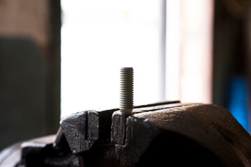 A threaded pin is clamped in the vice.
