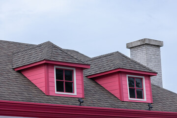 A red house with a chimney and two windows of garret house.