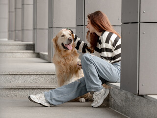 Teen Girl With Golden Retriever Sits In City During Spring