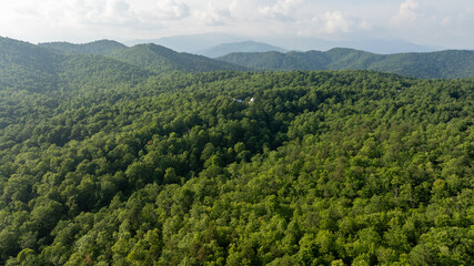 Aerial view of lush green mountains with winding roads and scattered houses, located in Black Mountain, North Carolina.