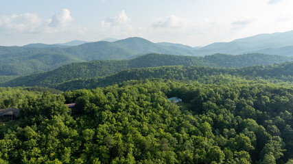 Aerial view of lush green mountains with winding roads and scattered houses, located in Black Mountain, North Carolina.