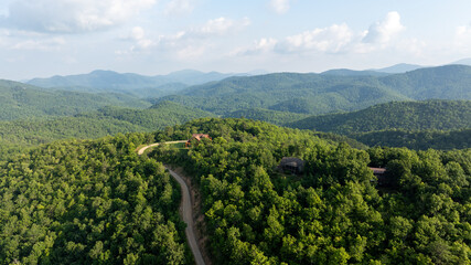 Aerial view of lush green mountains with winding roads and scattered houses, located in Black Mountain, North Carolina.