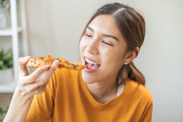 Happy meal with fast food, pleasure asian young woman, girl hold piece, enjoy eating delicious slice of pizza having takeaway at home relaxing resting, like taste good appetite, snack in lunch, dinner