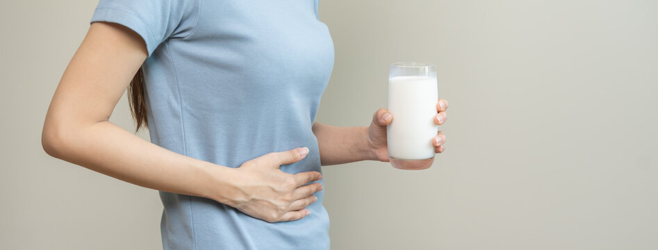 Pain, suffering asian young woman having a stomachache, abdominal pain or digestive, hand in holding belly after drink glass of milk. Lactose intolerance, allergy from dairy food, health care problem.