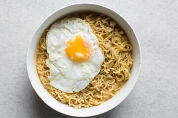overhead view of a bowl of ramen with a fried egg, top view of a runny egg with noodles