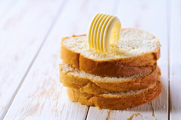 Slices of wheat bread and butter curls on a wooden table, selective focus.