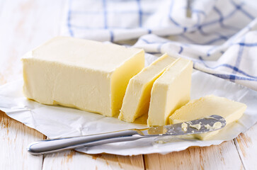 cut block butter on a white wooden table, selective focus. Stick of butter, cut.