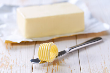 Tasty butter and knife on a kitchen table, selective focus. Butter curl on knife .