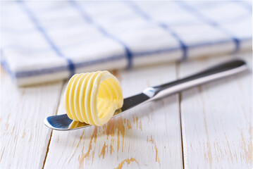 Knife with butter curls on a white wooden table, selective focus. Butter curl on knife .