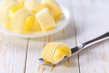 Butter curls in a plate on a white wooden table, selective focus.