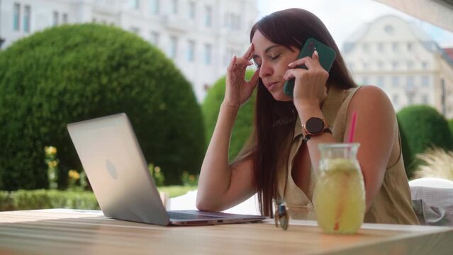 A businesswoman in outdoor cafe closes laptop gets bad news via email feeling stressed and annoyed about work

