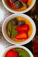 Foie gras in caramel sauce with fresh berries. Beautiful presentation of food in a restaurant. Close-up, vertical photograph.