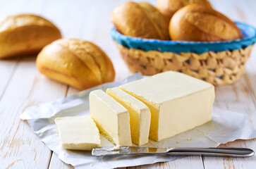 Basket of bread with butter on white wooden table.