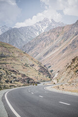 Fototapeta premium Automobile asphalt road in the mountains in the valley between rocky mountains, Pamir Highway in Tajikistan