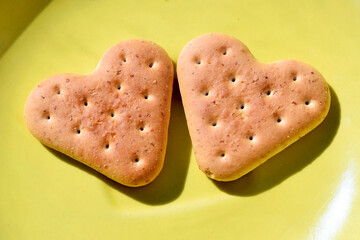 Two cookies in the shape of hearts lie on a plate