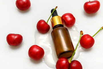 Lotion for body and face in glass container. Lying on spilled lotion. Red cherry.