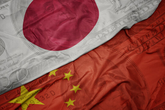 waving colorful flag of japan and national flag of china on the dollar money background. finance concept.