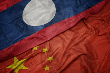 waving colorful flag of laos and national flag of china on the dollar money background. finance concept.