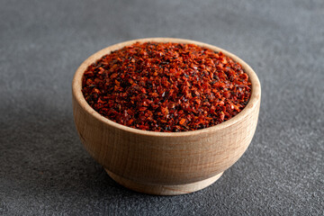 Red pepper flakes.Red chili peppers in wooden bowl on black background
