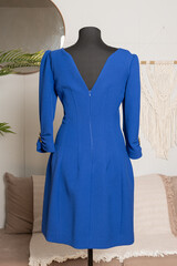 Elegant blue three-quarter sleeve dress with short. Rear view of the slit and zipper on a tailor's mannequin. Demonstration of women's clothing.