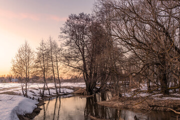 Obraz premium A snowy landscape with a river and trees