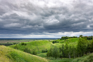 A cloudy sky with a green hillside in the background