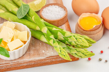 fresh bunch of asparagus on a kitchen table with ingredients for cooking healthy eating