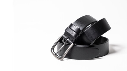 Twisted black leather belt with matted metal buckle isolated on white background. Fastened fashionable unisex, man or woman accessory for trousers, jeans, dress. Male luxury strap. Haberdashery goods