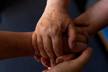 Fototapeta premium Close-up of a mother and her adult son's hands grasping each other, symbolizing family unity, support, and connection.