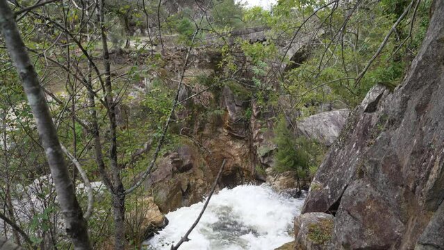 View of the ancient roman Ponte Mizarela, or Devils Bridge with a beautiful arch and picturesque waterfall, at the Peneda Geres National Park in Portugal, Europe