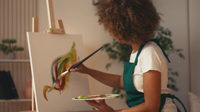 Professional woman painter making brushstrokes, painting on a canvas, art