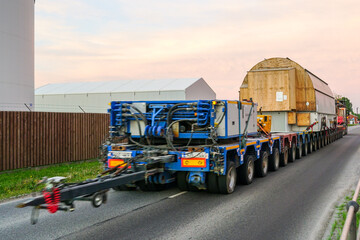 Very long specialized multi axle truck trailer carries very heavy oversize cargo, rear view