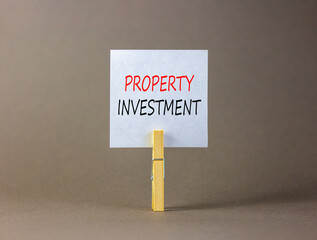 Property investment symbol. Concept words Property investment on beautiful white paper on wooden clothespin. Beautiful grey background. Business Property investment concept. Copy space.