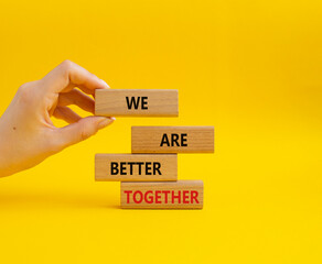 We are better together symbol. Wooden blocks with words We are better together. Beautiful yellow background. Businessman hand. We are better together concept. Copy space.