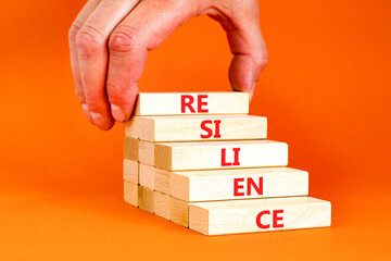 Resilience symbol. Concept word Resilience on beautiful wooden blocks. Businessman hand. Beautiful orange background. Business resilience concept. Copy space.