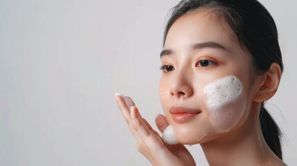 Asian model does facial cleansing young girl with foam on her face