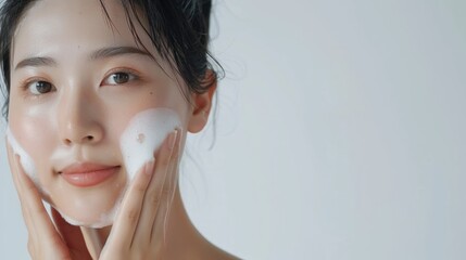 Asian model does facial cleansing young girl with foam on her face