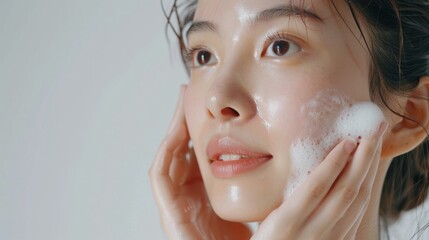 Asian model does facial cleansing young girl with foam on her face