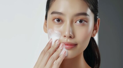 Asian model does facial cleansing young girl with foam on her face