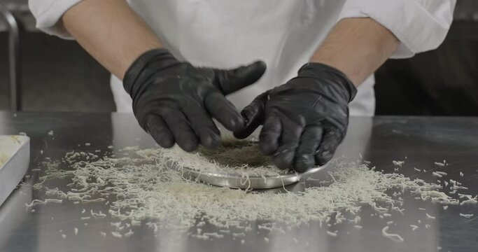 Traditional Turkish dessert kunefe or kunafa. Pastry chef puts kataifi dough in the copper plate with hands. Arabic sweets. Middle eastern national food desserts
