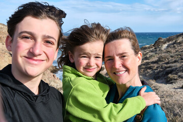 A Single-parent family takes a selfie with the sea in the background