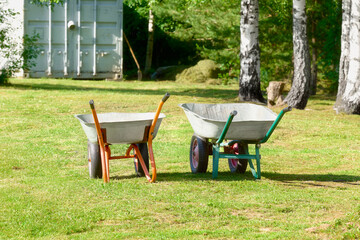 Two empty garden wheelbarrows on the mown grass.