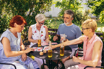 Group of elderly retired people playing bingo outside. Drinking beer and enjoying some time outside.