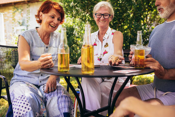 Group of elderly retired people playing bingo outside. Drinking beer and enjoying some time outside.